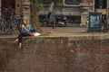 Young girl alone sitting on wall at the canalÃ¢â¬â¢s edge, eating ice cream in Amsterdam.